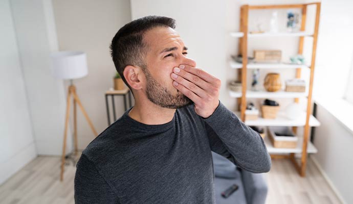 Man pinching his nose reacting to unpleasant musty odor indoors